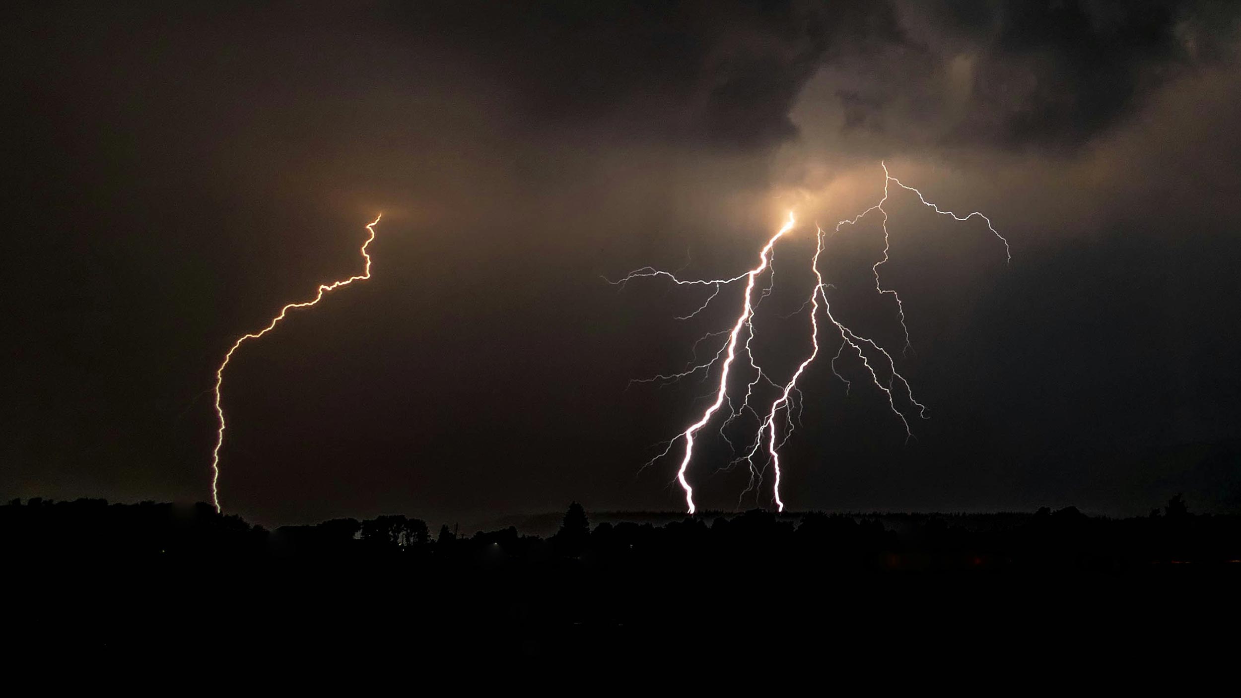 A home theater room with plush leather recliners facing a large screen displaying a vibrant superhero movie scene, providing an immersive viewing experience with surround sound and dim lighting.