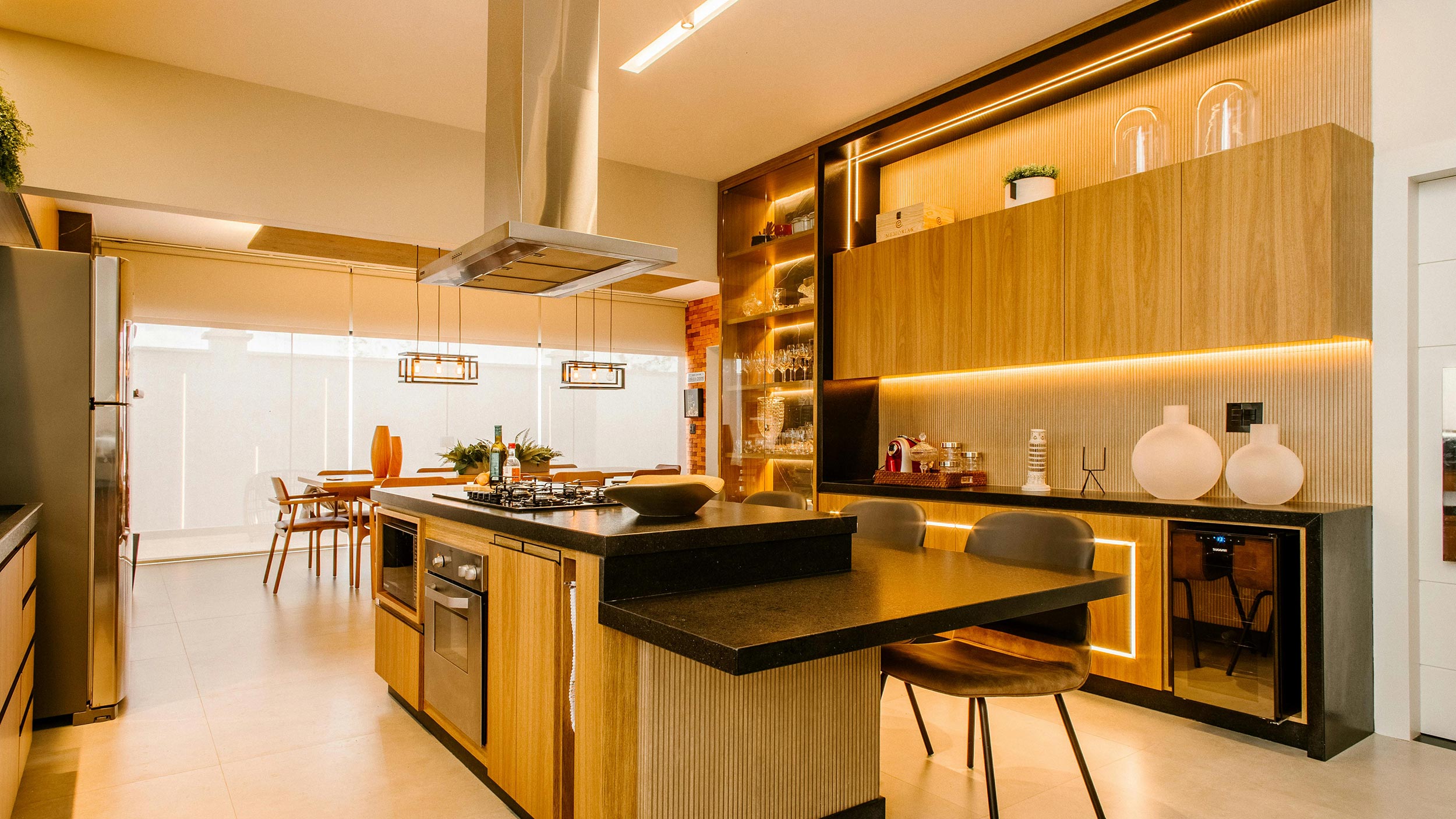 A cozy living room with a large stone fireplace, plush sofas, vibrant orange chairs, and a unique chandelier resembling tree branches with light bulbs, creating a warm and inviting atmosphere for relaxation and socializing.