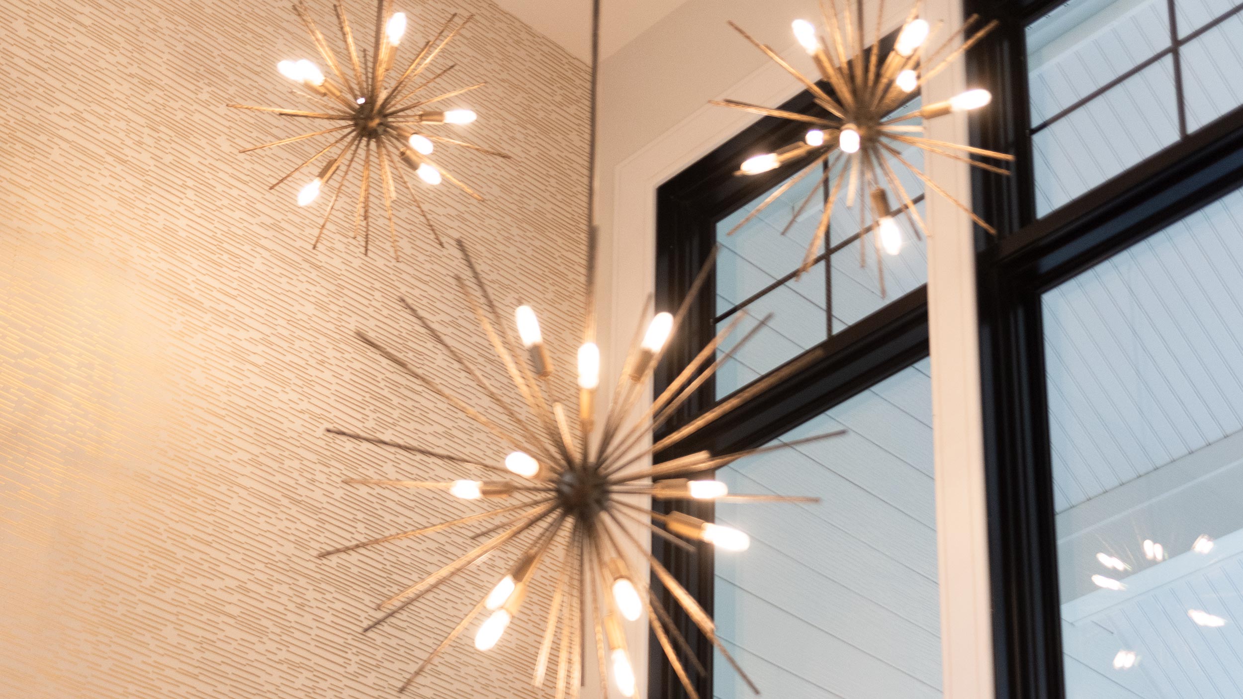 A security camera mounted under the eaves of a house, capturing surveillance footage and monitoring the outdoor surroundings on a cloudy day, with a green tree partially visible.